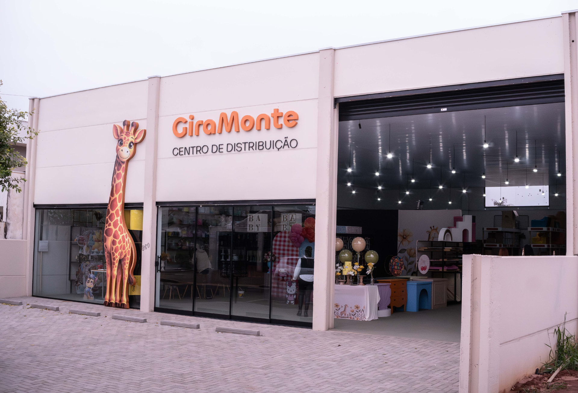 Fachada da loja GiraMonte Centro de Distribuição em Paranavaí, com placa laranja e girafa mascote na vitrine