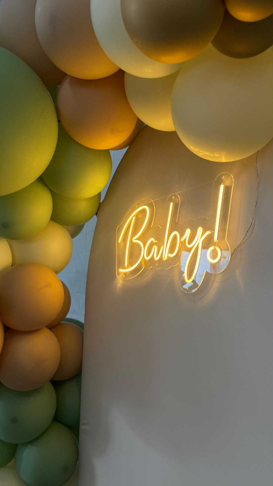 Detalhe do arco orgânico de balões em tons verdes e nude com letreiro neon Baby!